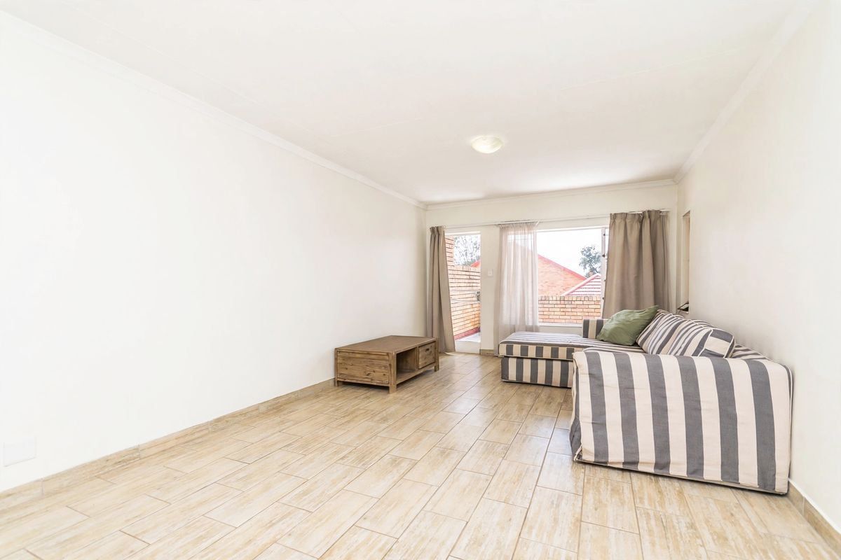 A bright living room featuring tiled flooring, a coved ceiling, and a sliding glass door providing access to an outdoor area.