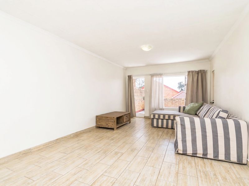 A bright living room featuring tiled flooring, a coved ceiling, and a sliding glass door providing access to an outdoor area.