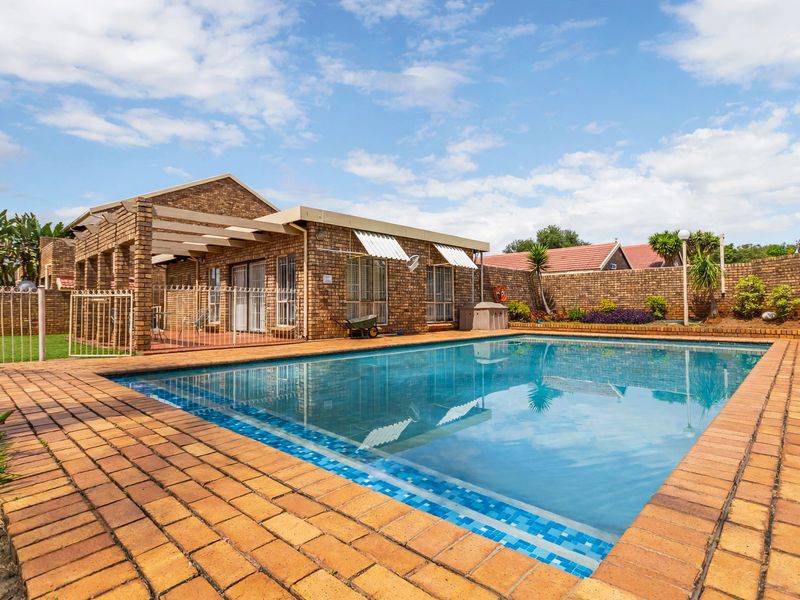 A well-maintained outdoor pool area featuring brick paving, a pergola, and a private brick boundary wall, perfect for outdoor relaxation.