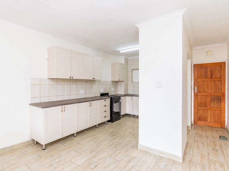 A clean, functional kitchen featuring light-toned cabinetry, tiled backsplash, and durable ceramic flooring, offering a blank canvas for modern updates.