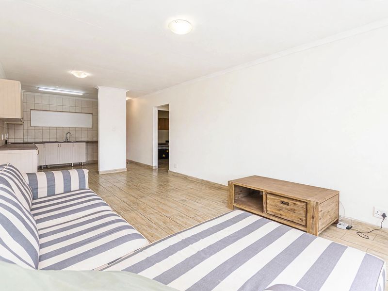 An open-plan living area featuring tiled flooring and a functional kitchen space with built-in cabinetry and tiled backsplash.