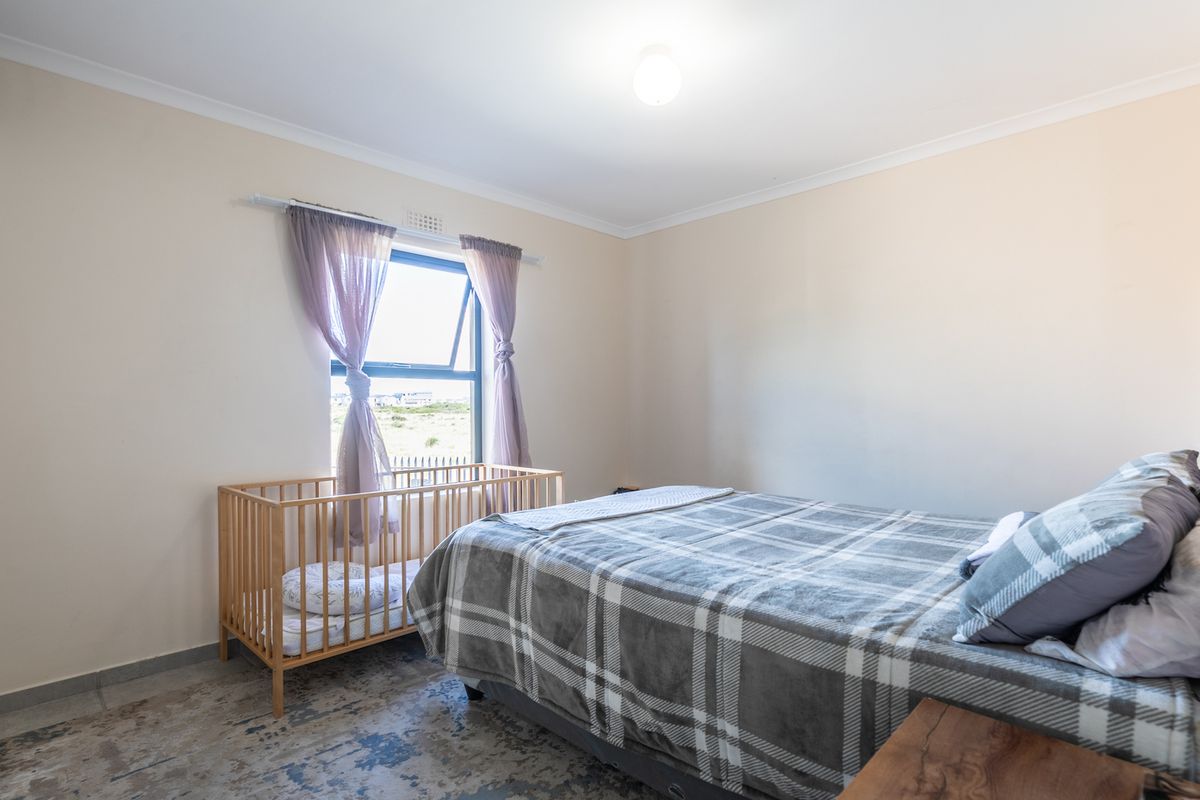 A well-maintained bedroom featuring neutral walls, tiled flooring, a built-in wardrobe, and a top-hung window providing natural light.