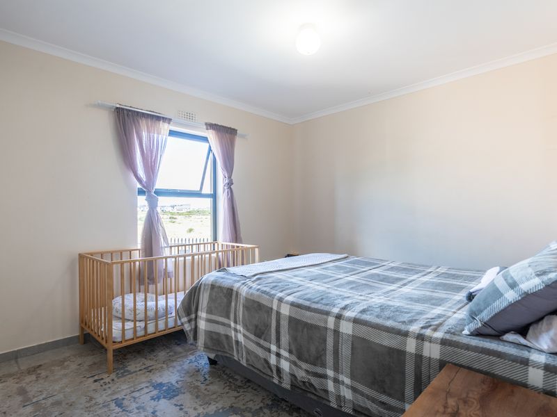 A well-maintained bedroom featuring neutral walls, tiled flooring, a built-in wardrobe, and a top-hung window providing natural light.