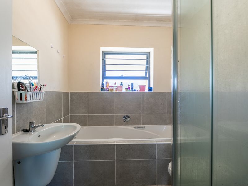A functional bathroom featuring a pedestal basin, a built-in bathtub with tiled surround, and a separate glass-enclosed shower area.