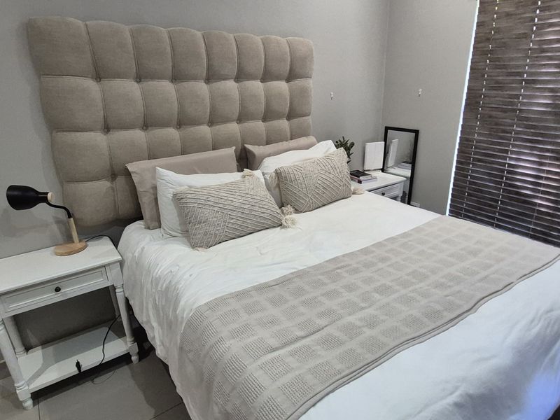 A well-maintained bedroom featuring neutral wall tones, tiled flooring, and fitted venetian blinds, providing a clean and comfortable living space.