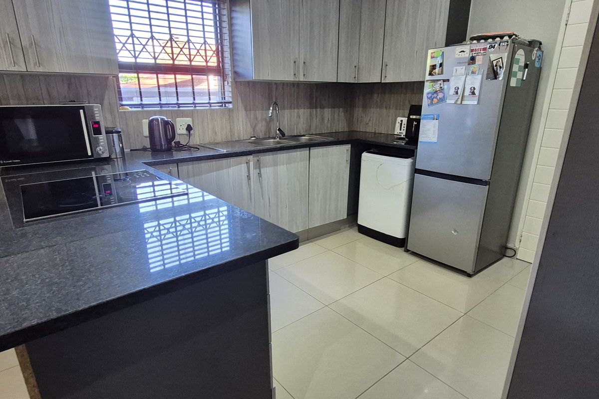 Modern kitchen featuring granite countertops, ample built-in cabinetry, and ceramic tile flooring, providing a functional and well-maintained workspace.