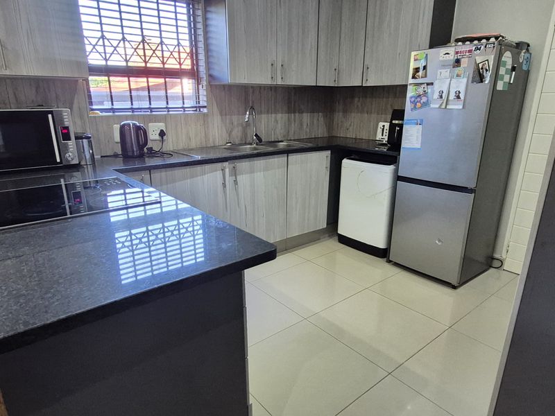 Modern kitchen featuring granite countertops, ample built-in cabinetry, and ceramic tile flooring, providing a functional and well-maintained workspace.