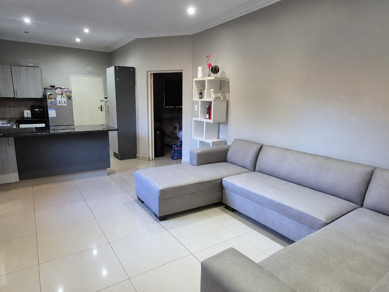 Open plan living area featuring a modern kitchen with granite countertops, tiled flooring, and recessed downlighting, creating a functional and cohesive space.