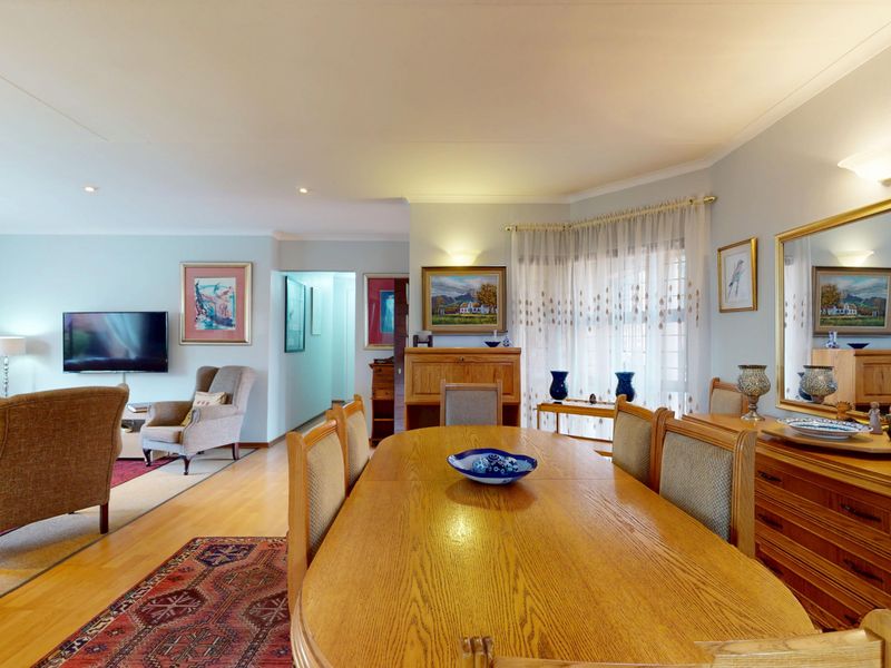 Spacious open-plan living and dining area featuring laminate flooring, recessed lighting, and a large wall-mounted mirror, creating a bright and functional living space.