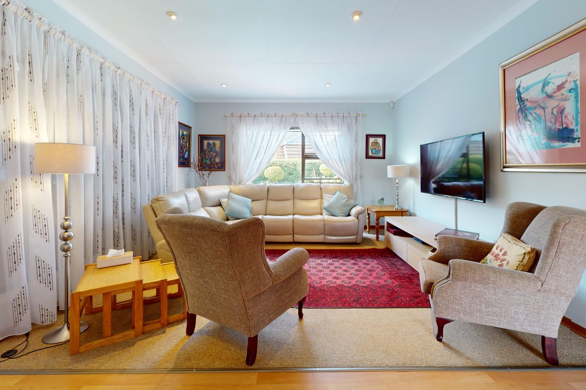 A comfortable living room featuring recessed downlighting, coved ceilings, and laminate flooring, providing a bright and inviting space for relaxation.