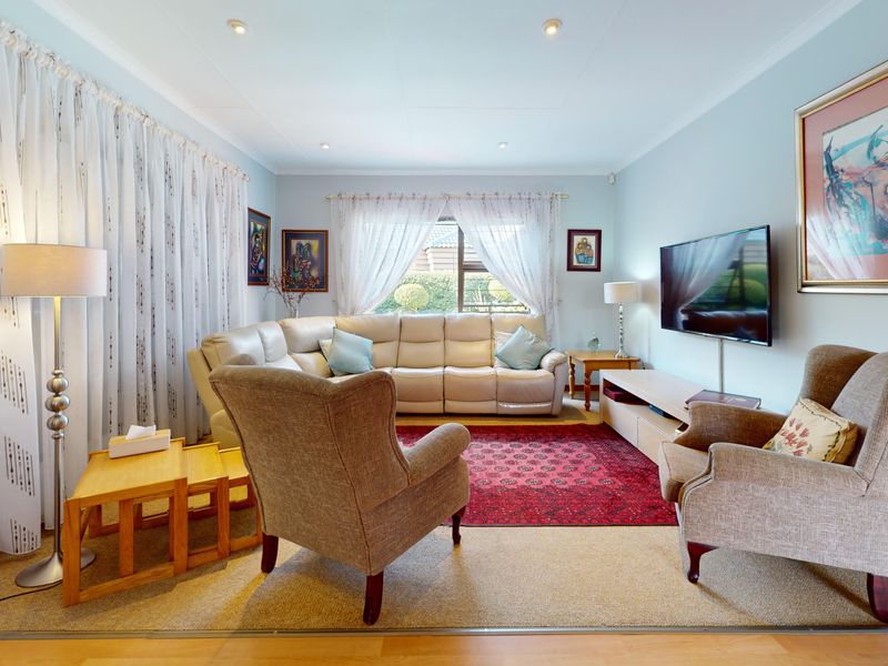 A comfortable living room featuring recessed downlighting, coved ceilings, and laminate flooring, providing a bright and inviting space for relaxation.