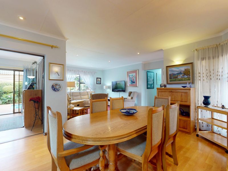 Spacious open-plan dining and living area featuring laminate flooring, recessed lighting, and seamless access to an outdoor patio through sliding glass doors.