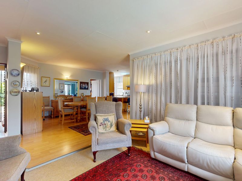 Spacious open-plan living and dining area featuring a mix of laminate and carpet flooring, recessed lighting, and direct access to an outdoor patio.