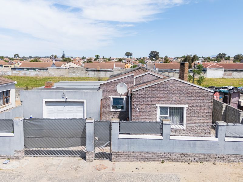 Front elevation of a single-story brick house featuring a tiled roof, attached garage, and a perimeter boundary wall.