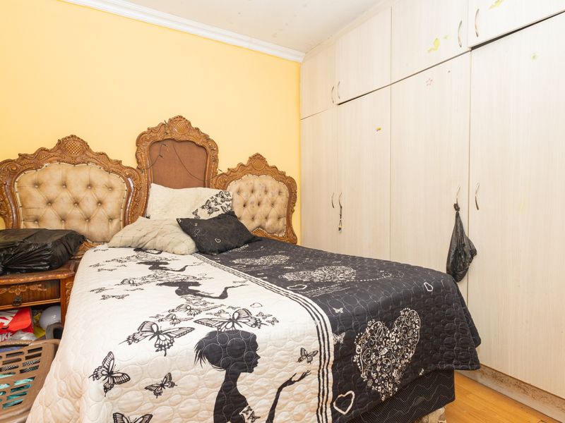 A bedroom featuring built-in cupboards and laminate flooring, requiring cosmetic updates to the walls and ceiling to improve the overall aesthetic.