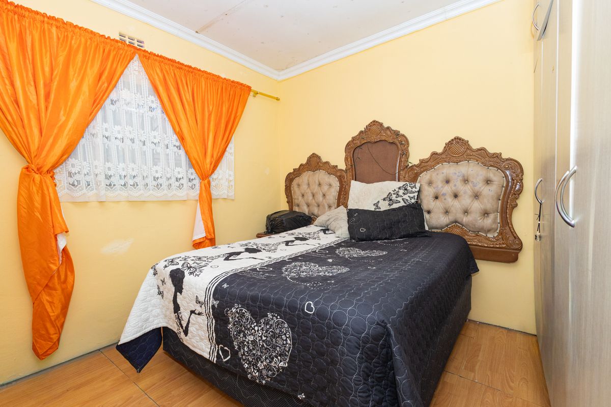 A bedroom featuring laminate flooring, built-in wardrobe storage, and decorative ceiling cornicing, requiring minor cosmetic updates to the walls and ceiling.