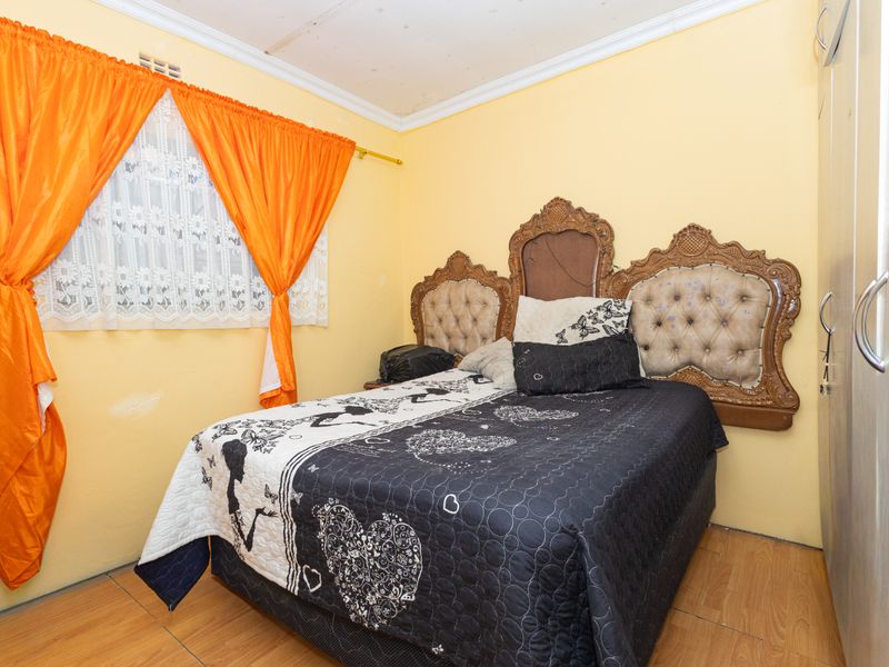 A bedroom featuring laminate flooring, built-in wardrobe storage, and decorative ceiling cornicing, requiring minor cosmetic updates to the walls and ceiling.