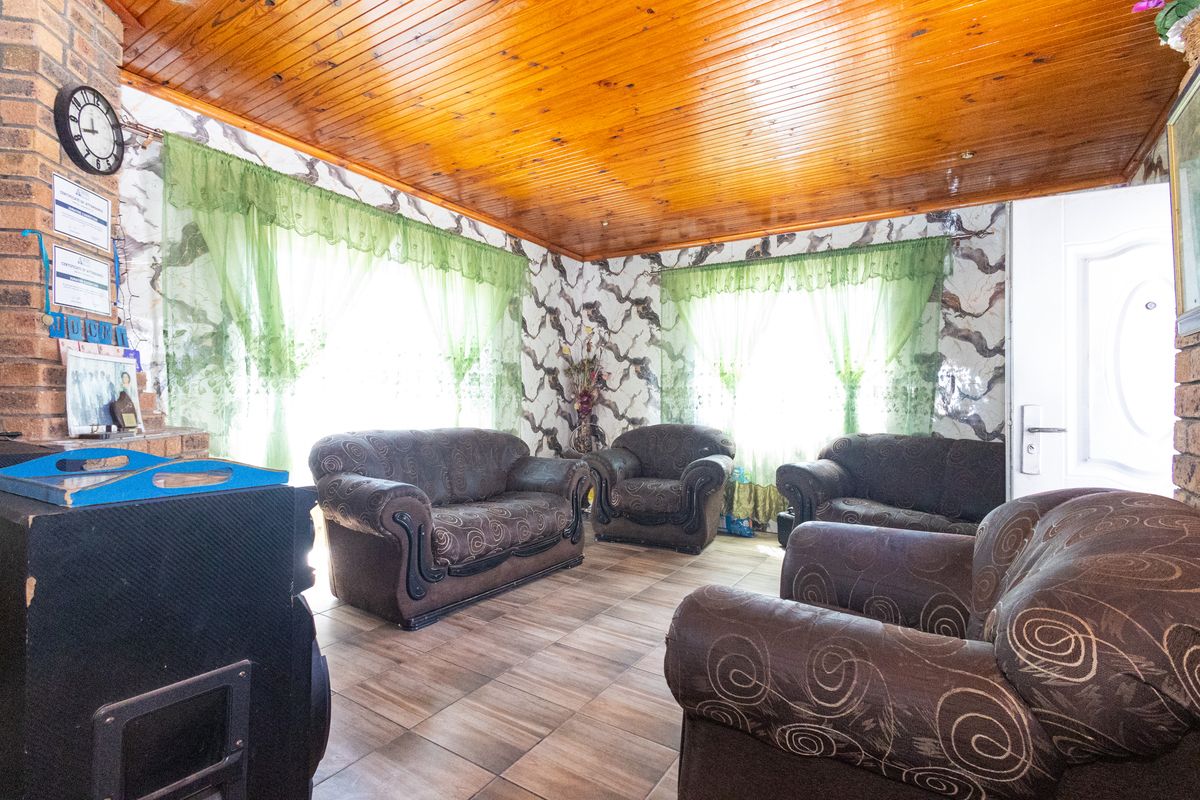 Living room featuring exposed brickwork, tiled flooring, and a timber-clad ceiling, offering a rustic aesthetic with potential for modern updates.