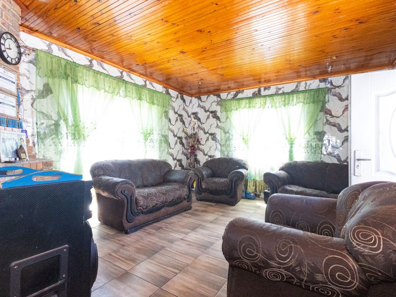 Living room featuring exposed brickwork, tiled flooring, and a timber-clad ceiling, offering a rustic aesthetic with potential for modern updates.