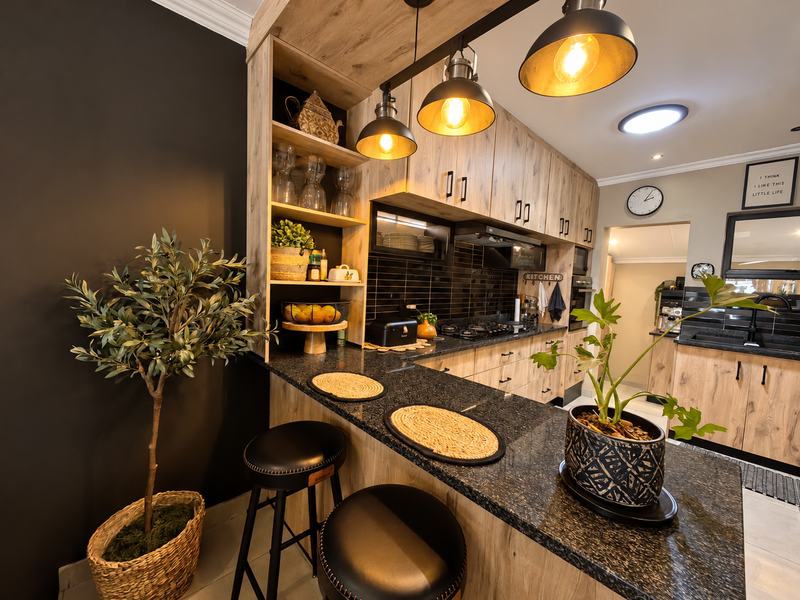 Modern kitchen featuring wood-look cabinetry, granite countertops, a breakfast bar, and integrated gas hob with stylish pendant lighting.