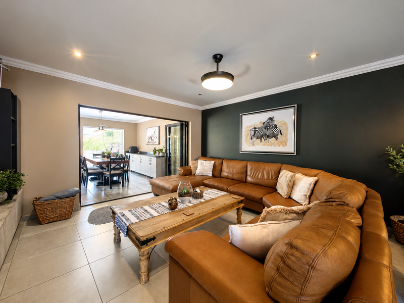 Spacious open-plan living area featuring tiled floors, recessed lighting, and bi-fold doors leading to an adjacent dining space.