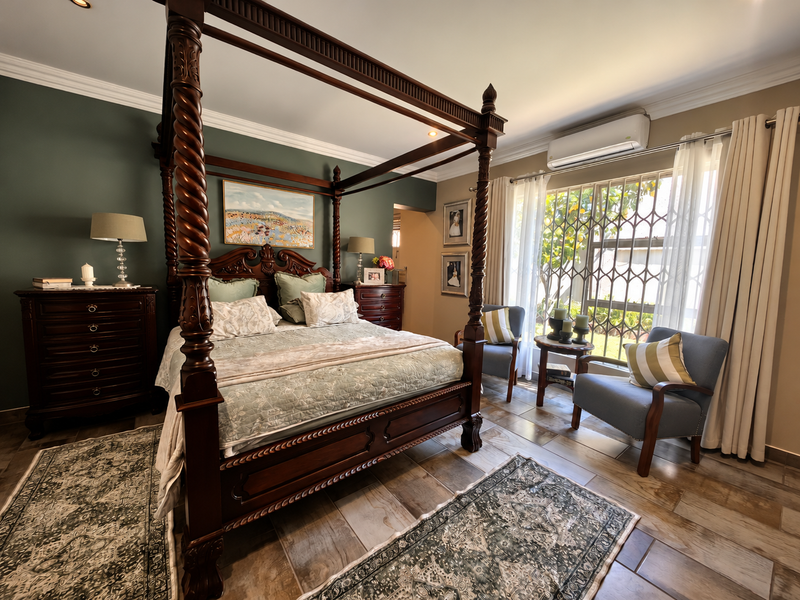 A well-maintained bedroom featuring tiled flooring, crown molding, recessed lighting, and a wall-mounted split-system air conditioner with security gate access to the exterior.