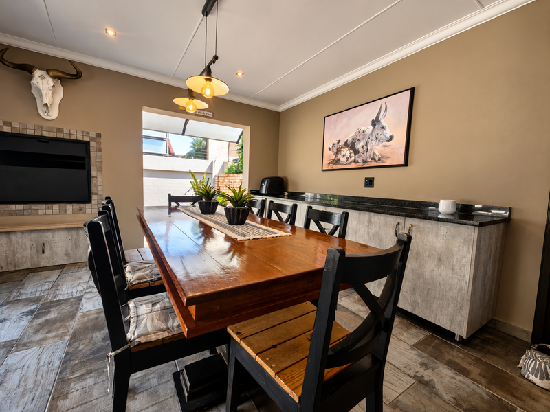 A well-maintained dining area featuring a built-in fireplace, custom cabinetry with granite countertops, tiled flooring, and stylish pendant lighting.