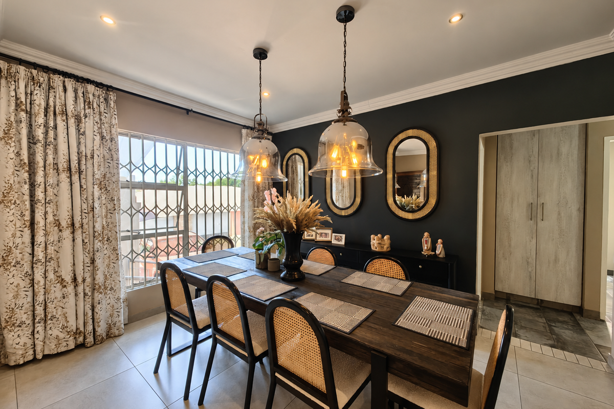 A well-appointed dining room featuring tiled floors, elegant pendant lighting, recessed ceiling lights, and built-in cabinetry, complemented by a secure window with a metal gate.