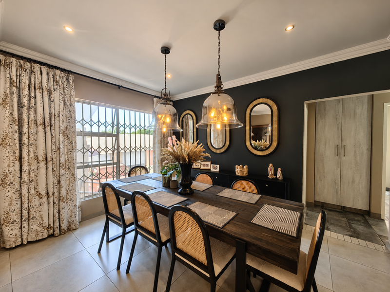 A well-appointed dining room featuring tiled floors, elegant pendant lighting, recessed ceiling lights, and built-in cabinetry, complemented by a secure window with a metal gate.