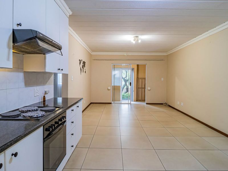 Spacious open-plan kitchen and living area featuring tiled floors, built-in cabinetry with granite countertops, and direct access to an outdoor space via sliding doors.