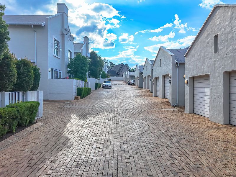 A view of the complex driveway featuring paved surfaces, multiple garage access points, and well-maintained exterior building facades.