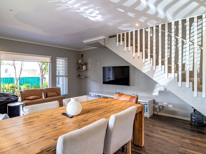 Open plan living and dining area featuring laminate flooring, a modern staircase, and direct access to the outdoor space through sliding glass doors.