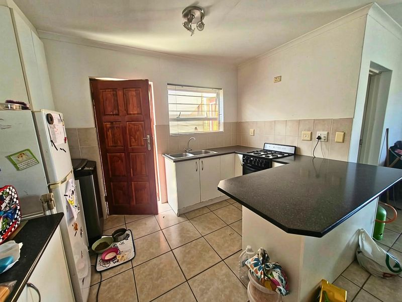 Functional kitchen featuring tiled flooring, laminate countertops, a double sink, and a gas stove with a tiled backsplash.
