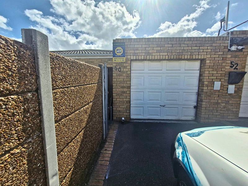 Exterior view of a single garage featuring a brick facade, sectional door, and integrated security alarm system.