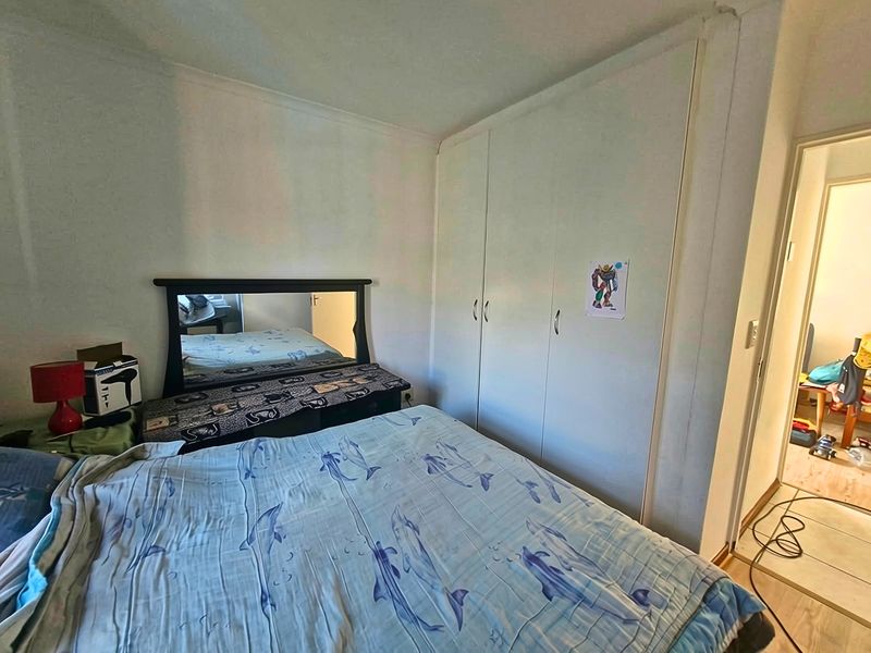 A functional bedroom featuring built-in cupboards and neutral wall finishes, offering a practical layout for comfortable living.