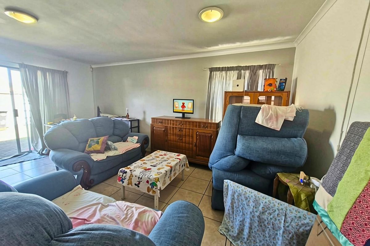 A spacious living room featuring tiled flooring, coved ceiling cornices, and a sliding glass door providing access to the exterior.