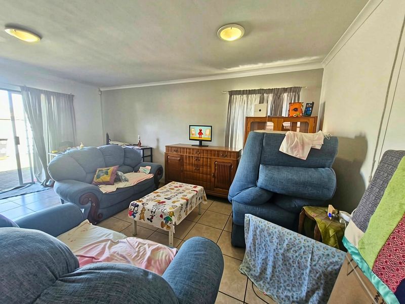 A spacious living room featuring tiled flooring, coved ceiling cornices, and a sliding glass door providing access to the exterior.