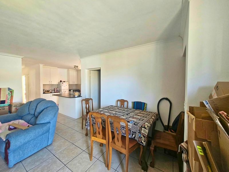 An open-plan living and dining area featuring tiled flooring and a connected kitchen with built-in cabinetry and a central island.