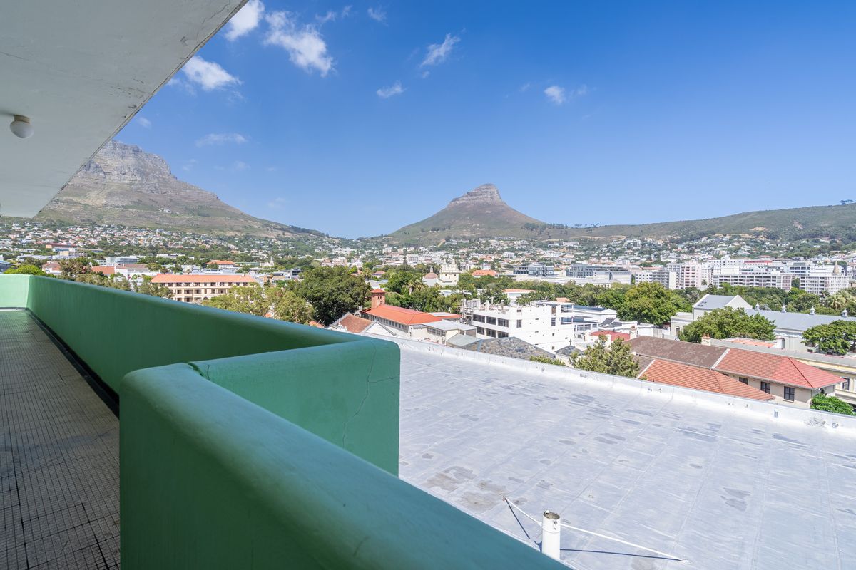 Spacious balcony offering panoramic views of the city and surrounding mountains, featuring a tiled floor and a solid protective railing.