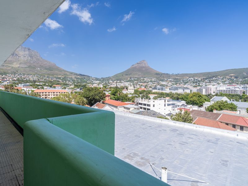 Spacious balcony offering panoramic views of the city and surrounding mountains, featuring a tiled floor and a solid protective railing.