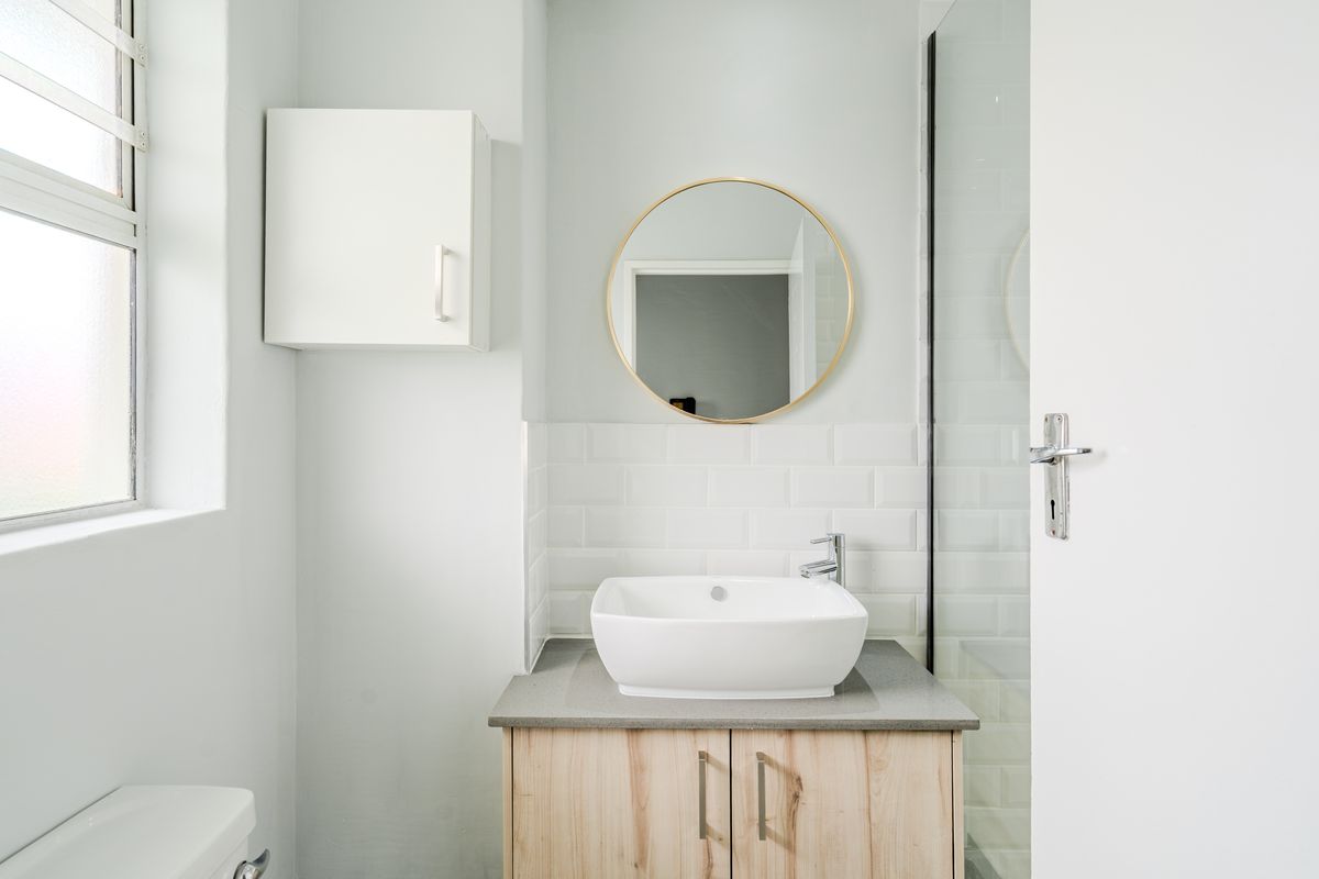 Modern bathroom featuring a vessel sink on a wooden vanity, subway tile backsplash, and a glass-enclosed shower area.