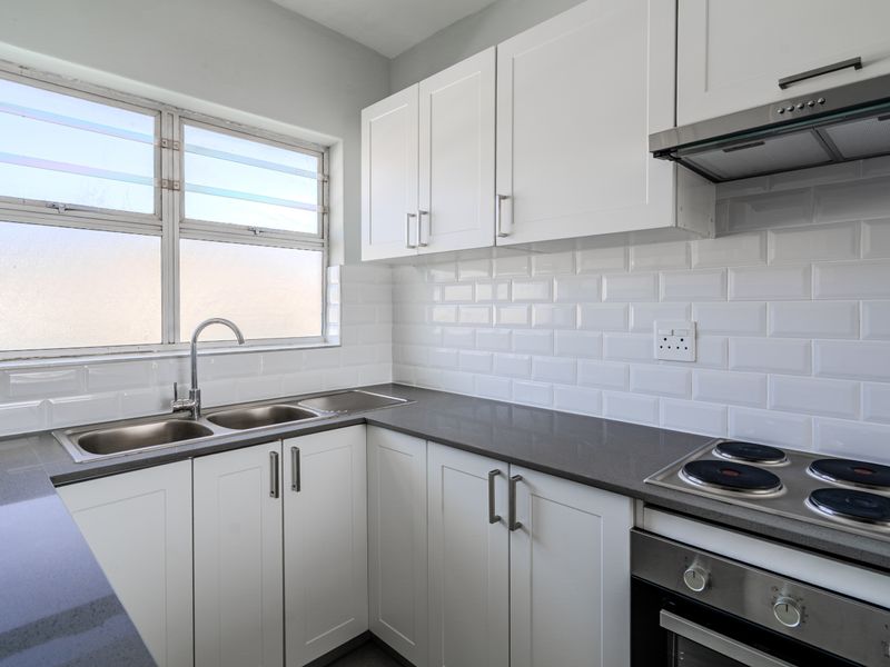 Modern, well-maintained kitchen featuring white shaker cabinetry, subway tile backsplash, dark stone countertops, and integrated stainless steel appliances.
