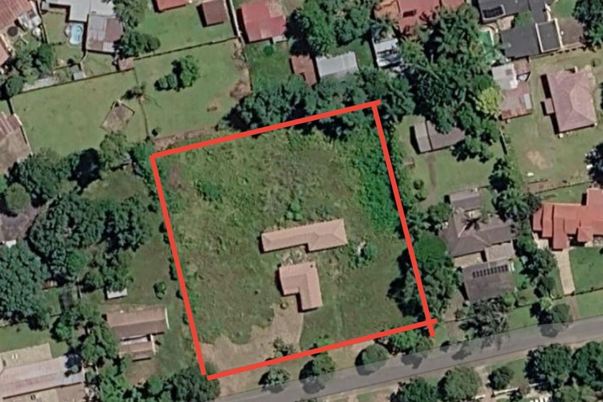 Aerial view of a residential vacant land plot featuring existing structures, surrounded by established neighborhood properties.