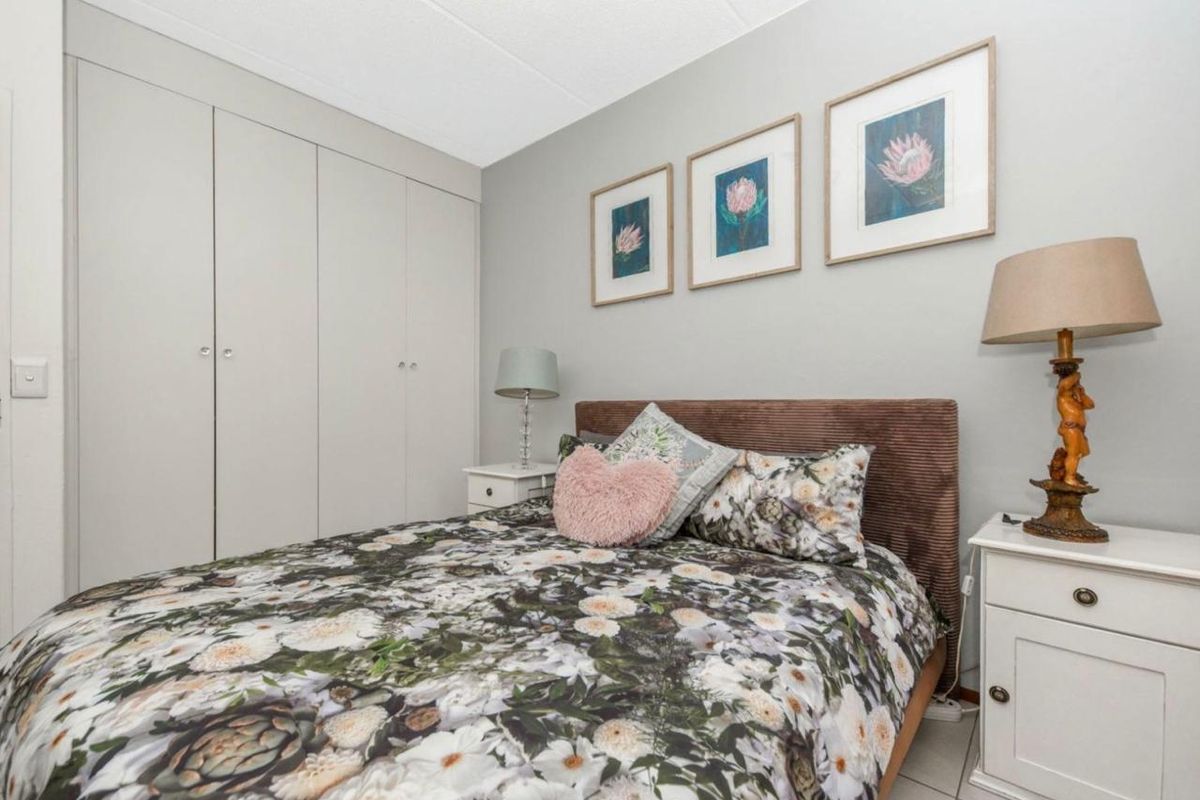 A well-maintained bedroom featuring neutral wall tones, tiled flooring, and ample built-in cupboard storage space.