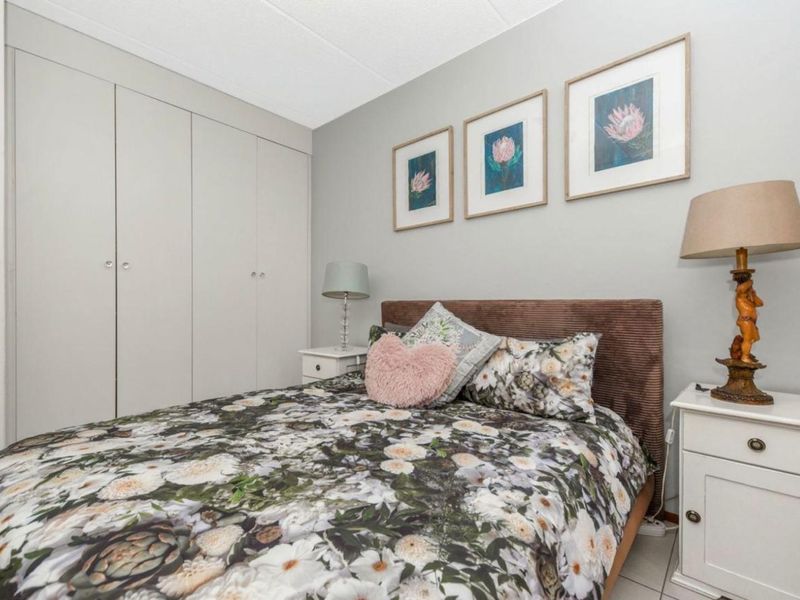 A well-maintained bedroom featuring neutral wall tones, tiled flooring, and ample built-in cupboard storage space.