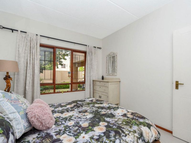 A well-lit bedroom featuring a timber-framed window with security bars and a standard internal door, offering a functional and comfortable living space.
