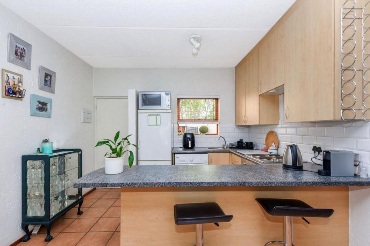 A functional kitchen featuring light wood cabinetry, granite countertops, a subway tile backsplash, and a breakfast bar island with tiled flooring.