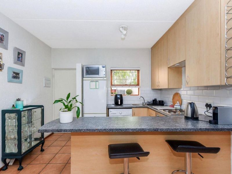 A functional kitchen featuring light wood cabinetry, granite countertops, a subway tile backsplash, and a breakfast bar island with tiled flooring.