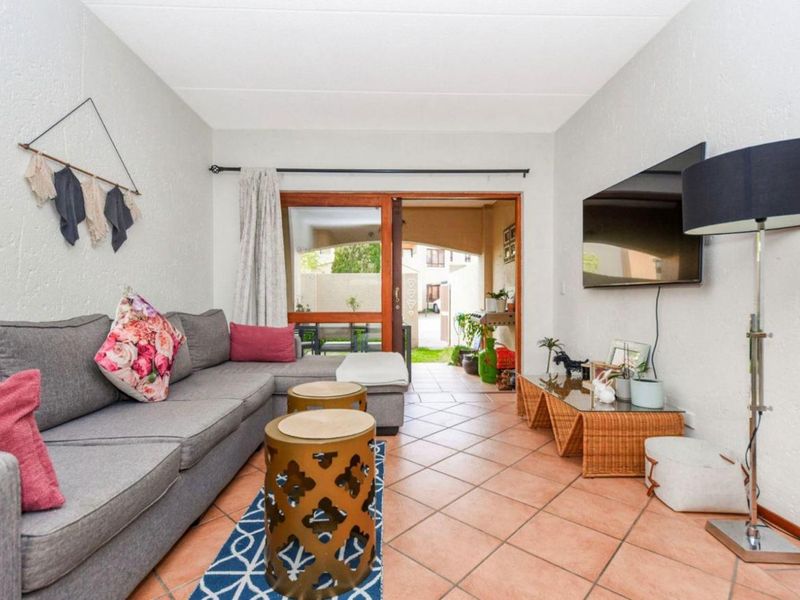 A living room featuring tiled flooring and a sliding glass door that provides access to an outdoor patio area.