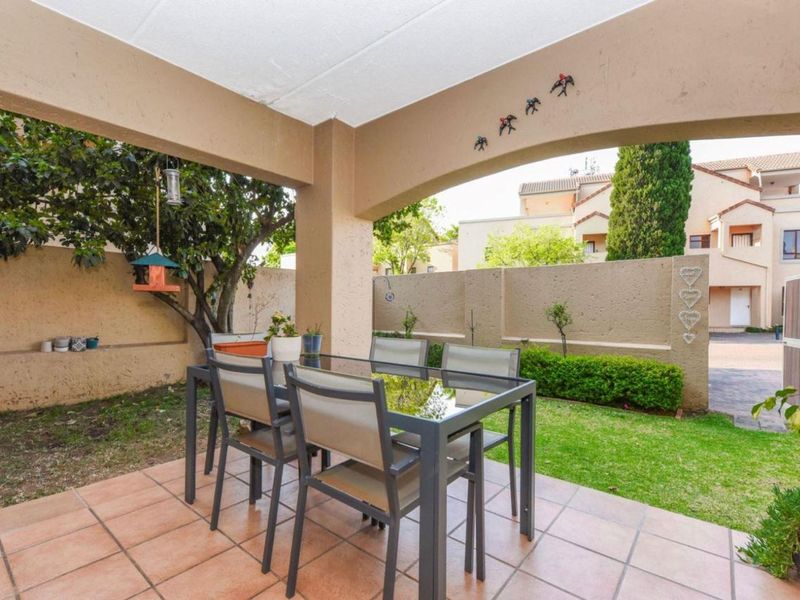 A covered patio area featuring tiled flooring, overlooking a private garden with a boundary wall.
